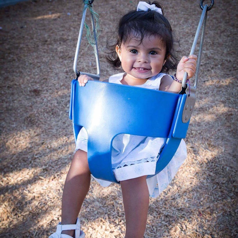 A little girl in a blue-seat of a swing whose mom has PCOS