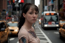 A woman standing in the middle of a busy city street looking at the camera