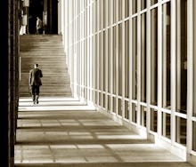 A man in a suit going through a hallway with bars on either side about to go up a large flight of st...