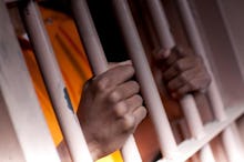 A prisoner's hands holding on to their cell bars from the inside