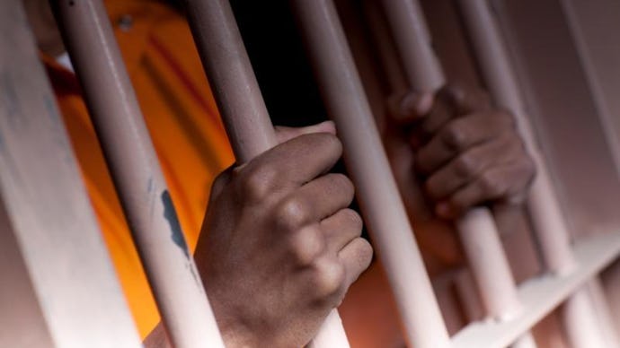 A prisoner's hands holding on to their cell bars from the inside