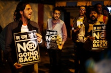 Indian gay rights activists posing with "no going back" signs 
