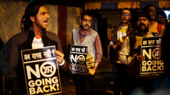 Indian gay rights activists posing with "no going back" signs 