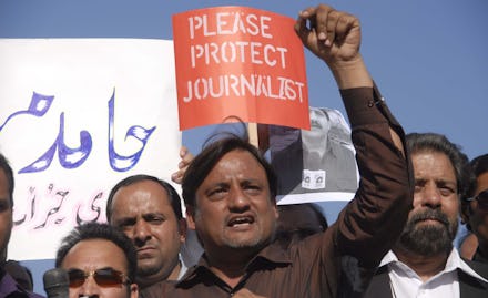 A group of protesters holding a 'Please Protect Journalists' poster in a country with no 'Free' Pres...