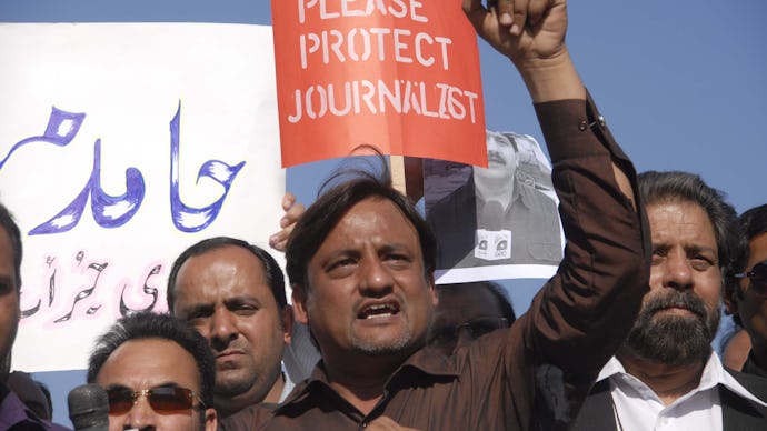 A group of protesters holding a 'Please Protect Journalists' poster in a country with no 'Free' Pres...
