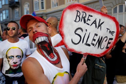 A man holding a protest banner with "Break the silence" text