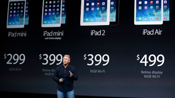 A man talking about Apple's four iPad products, that are visible on a wall behind him, with their pr...