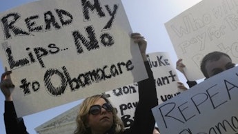 Protesters, with a woman holding a sign that says read my lips no to obamacare