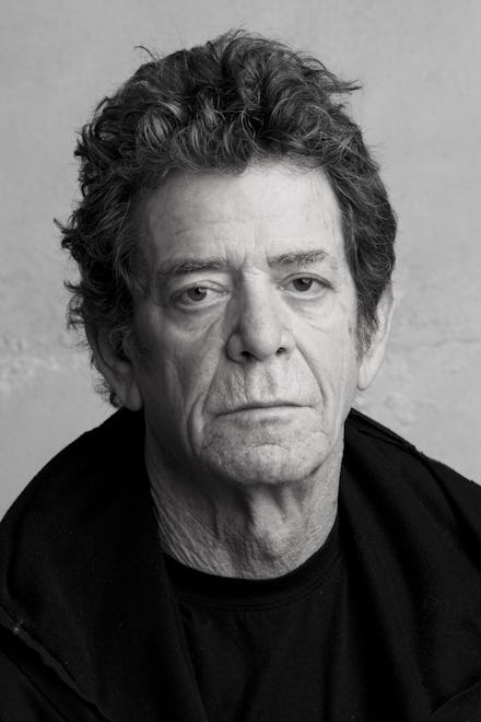 A closeup of Lou Reed in black and white wearing a plain black sweater and black jacket