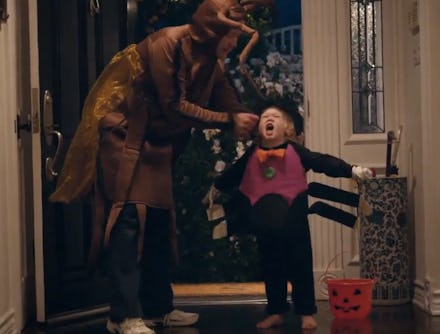 A dad dressed as a cockroach adjusting the spider costume of a child in their home
