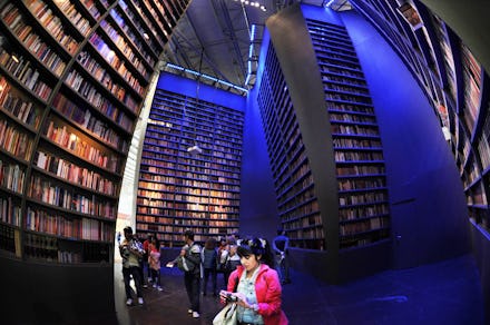 Fish eye view of people browsing a large library lit by neon blue lighting