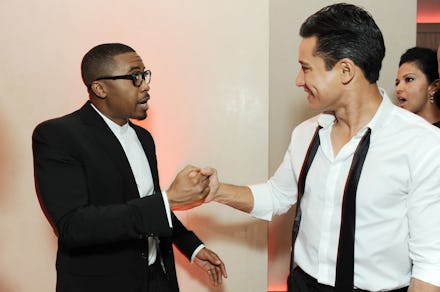Nas in a suite shaking hands with Mario Lopez in a white shirt with his bowtie untied hanging around...