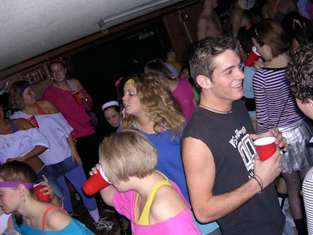 A college party, with a group of girls dressed in 80s attire, all attendees drinking from red solo c...