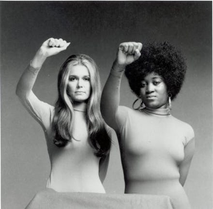 White and black women holding out their hands in a fist