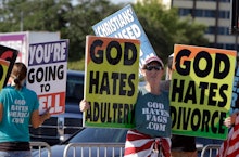 Protesters from the Westboro Baptist Church with signs that say "God hates adultery" and offensive s...