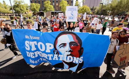 A crowd in the San Francisco ICE protests holding a poster with a picture of Obama and the text 'Sto...