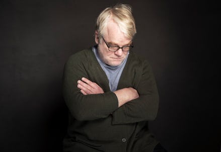 Philip Seymour Hoffman with his arms crossed in front of a black background