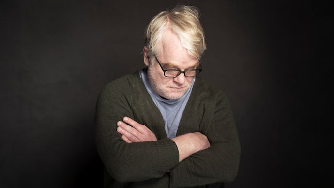 Philip Seymour Hoffman with his arms crossed in front of a black background
