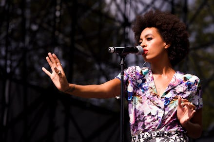Solange Knowles in a floral dress performing with a microphone in front of her