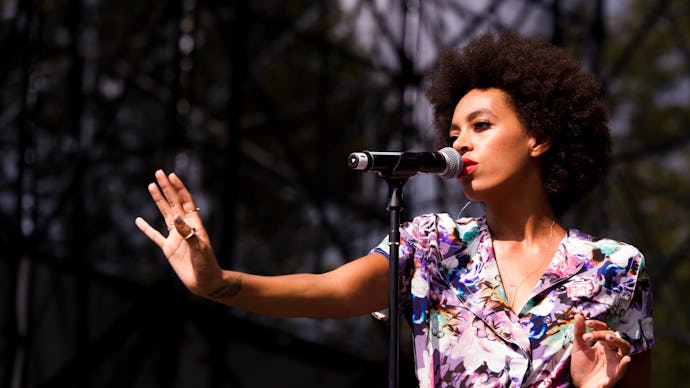 Solange Knowles in a floral dress performing with a microphone in front of her