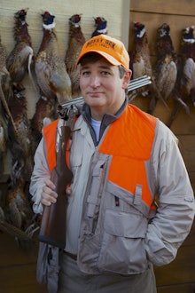 Ted Cruz holding a hunting riffle and birds behind him