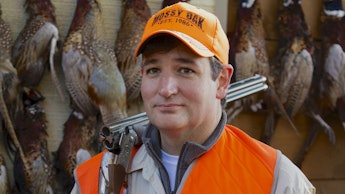 Ted Cruz holding a hunting riffle and birds behind him