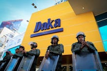 Police officers with helmets and shields standing in front of a Daka store in Venezuela 