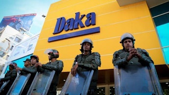 Police officers with helmets and shields standing in front of a Daka store in Venezuela 
