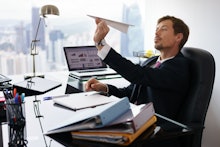 A man throwing a paper airplane in his office due to his pointless work