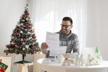 A man smiling and holding a form and ready to apply for a new job next to a Christmas tree