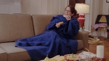 Tina Fey lying on a couch covered with a blue blanket on a Friday Night