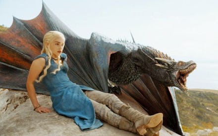 Daenerys Targaryen semi-sitting on a stone next to Drogon 