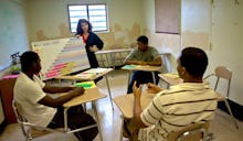 A teacher giving a lesson to prisoners in a make-shift classroom