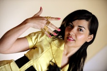 Sheryl Sandberg posing in a yellow and black outfit showing the rings on her hand