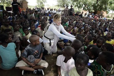 Madonna on her trip to Africa, surrounded by children, talking to one of them