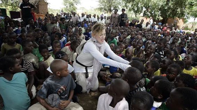 Madonna on her trip to Africa, surrounded by children, talking to one of them