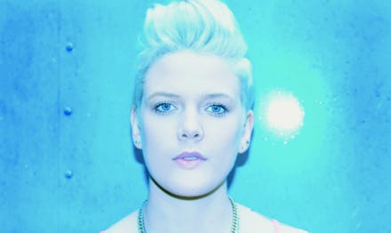 Australian singer Betty Who's close-up, with a light-blue backdrop and light towards her face. 