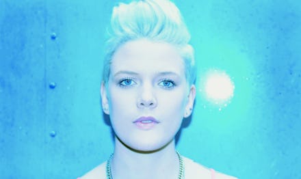 Australian singer Betty Who's close-up, with a light-blue backdrop and light towards her face.