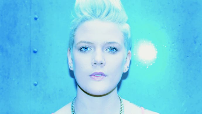 Australian singer Betty Who's close-up, with a light-blue backdrop and light towards her face. 