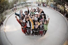 A group of Afghan children whose lives have been changed through skateboarding posing and waving wit...