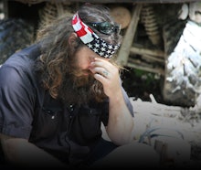Phil Robertson from Duck Dynasty sitting on the floor with his hand covering his face as if in disap...
