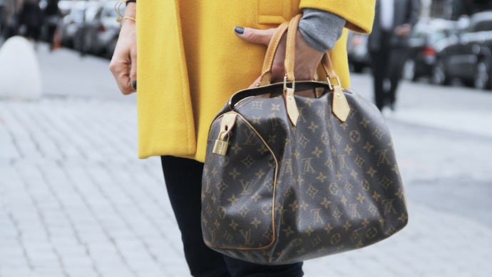 A woman in a yellow jacket holding a leather designer purse