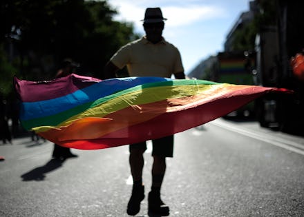 A 20-something person on a street waving with the LGBT flag