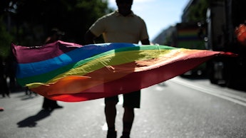 A 20-something person on a street waving with the LGBT flag
