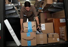 A UPS employee taking holiday gift packages and Amazon boxes out of the delivery van