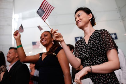 Two women in a large crowd happily smiling and waving with two pocket-sized American flags