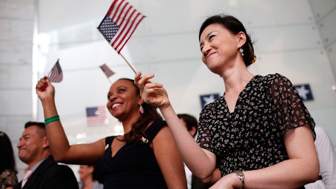 Two women in a large crowd happily smiling and waving with two pocket-sized American flags