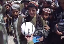 Tom Abood, a young Australian soldier serving in Afghanistan giving a ball to a group of local kids.