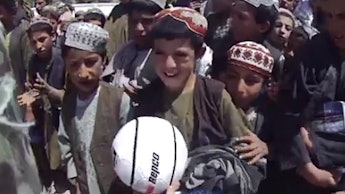 Tom Abood, a young Australian soldier serving in Afghanistan giving a ball to a group of local kids.