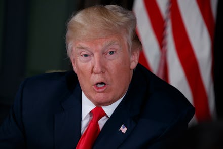 A closeup of Donald Trump speaking in a suit and tie with the U.S. flag behind him